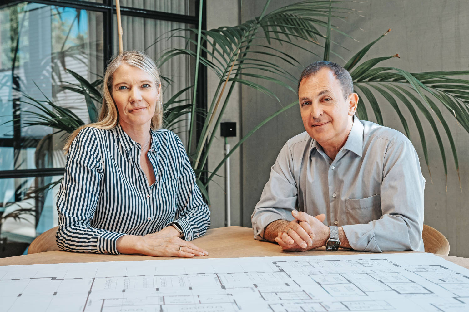 Akzenta Immobilien Mitarbeiterin und Mitarbeiter sitzen am Tisch mit Bauplänen – Beratung im gewerblichen Immobilienhandel